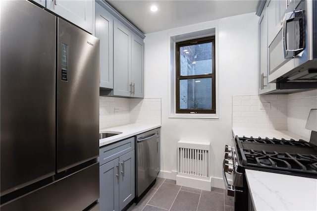 kitchen with baseboards, stainless steel appliances, tasteful backsplash, and gray cabinetry