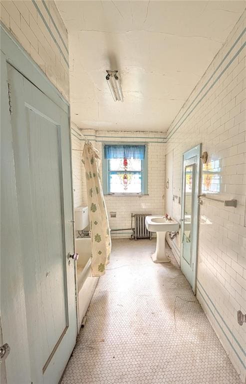 bathroom featuring brick wall, radiator heating unit, lofted ceiling, tile patterned floors, and shower / bath combination with curtain