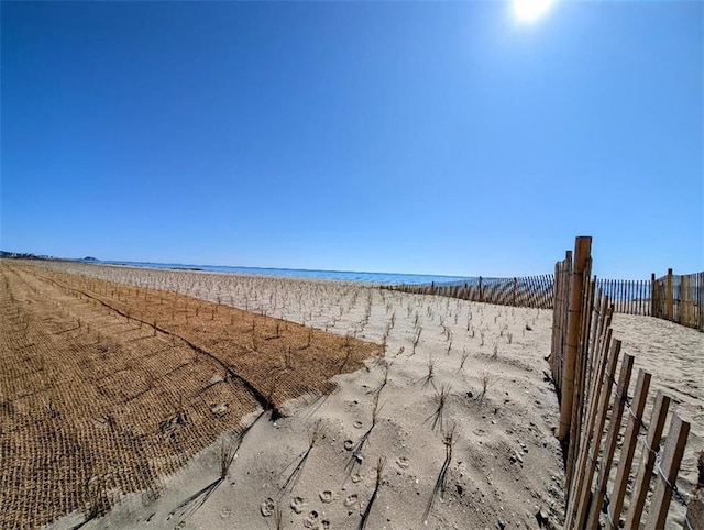 view of water feature with a beach view and fence