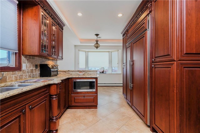 kitchen with built in appliances, light stone counters, decorative light fixtures, backsplash, and glass insert cabinets