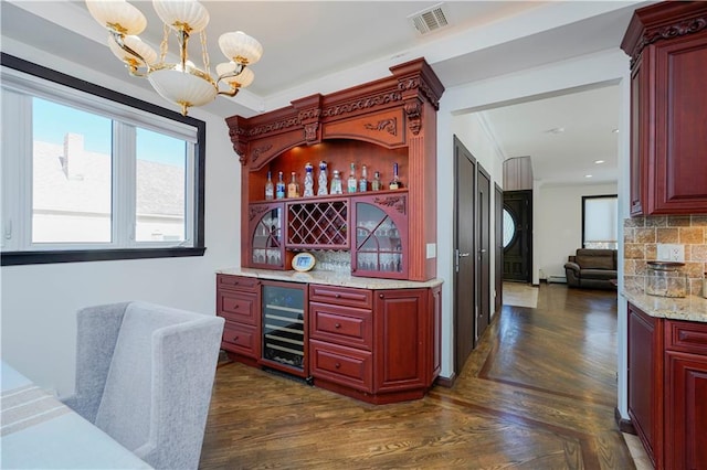 bar with beverage cooler, visible vents, dark wood-style floors, a bar, and a chandelier