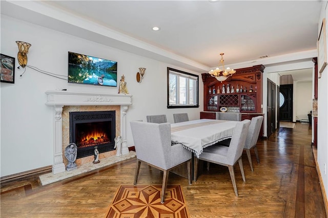 dining area featuring a warm lit fireplace, visible vents, dark wood finished floors, a chandelier, and recessed lighting