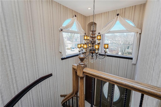 stairs featuring recessed lighting, wallpapered walls, and an inviting chandelier