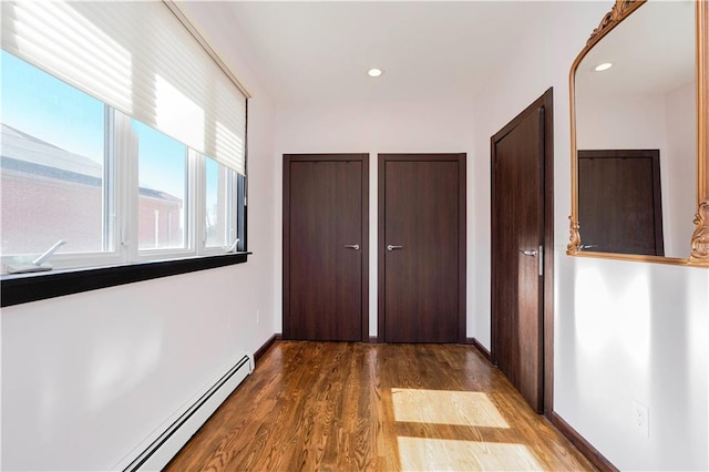 hallway featuring a baseboard radiator, baseboards, recessed lighting, and wood finished floors