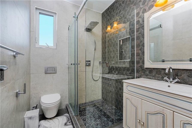 full bathroom featuring toilet, a stall shower, tile walls, and vanity