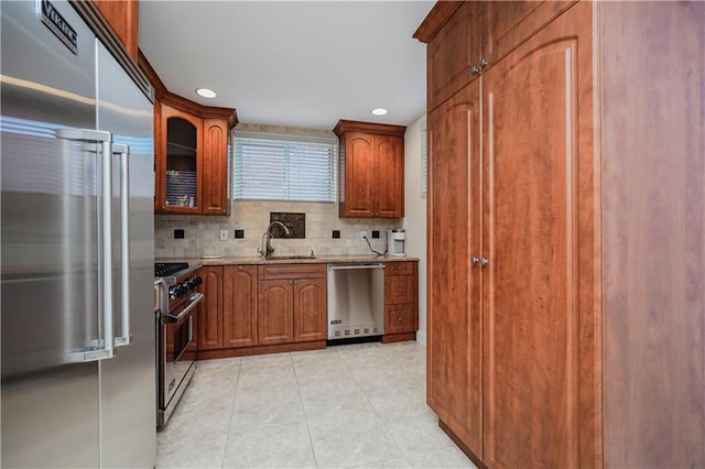 kitchen with premium appliances, light stone counters, light tile patterned floors, tasteful backsplash, and a sink