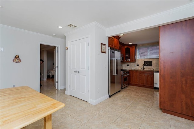 kitchen featuring visible vents, premium appliances, backsplash, crown molding, and a sink