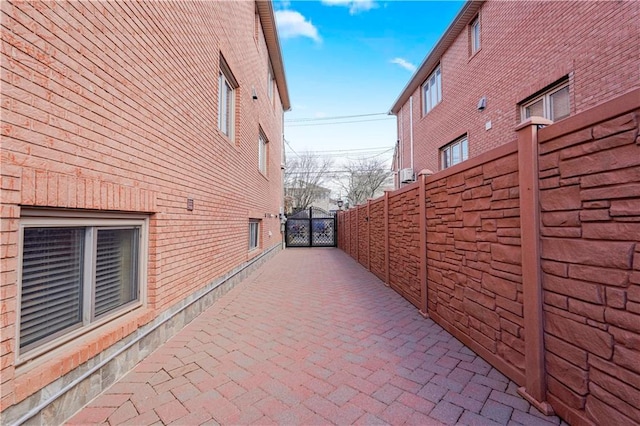 view of side of property with brick siding, fence, and a gate