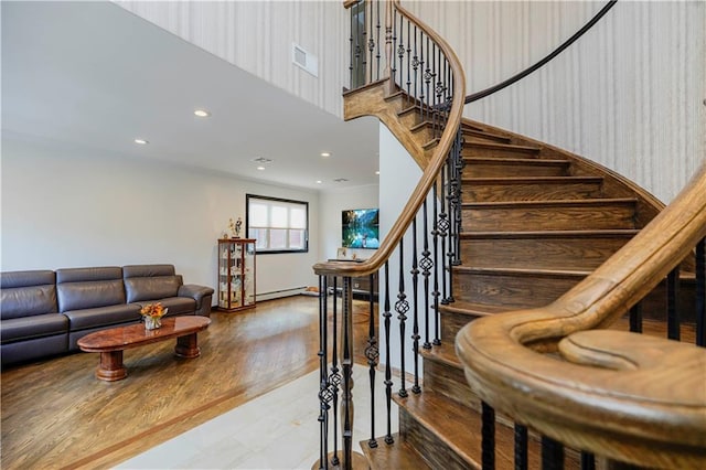 stairs with a baseboard radiator, visible vents, wood finished floors, and recessed lighting