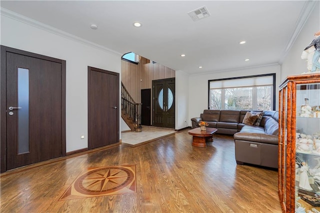 living room with ornamental molding, visible vents, stairway, and wood finished floors