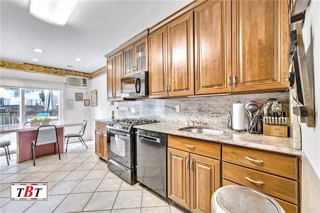 kitchen featuring brown cabinetry, a sink, black appliances, and a wall mounted AC