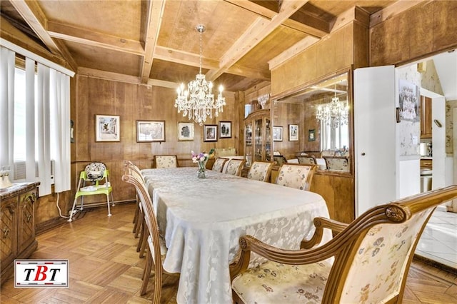 dining area featuring beam ceiling, coffered ceiling, a notable chandelier, and wood walls