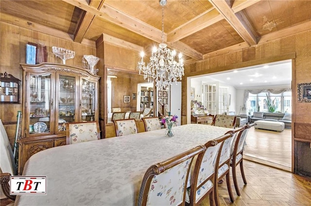 dining space featuring wooden walls, a chandelier, coffered ceiling, and beam ceiling