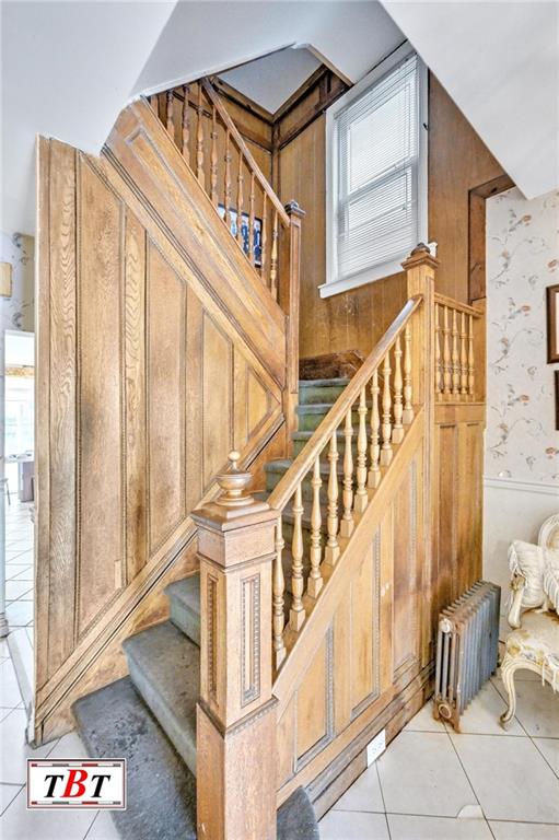 stairway featuring radiator, a wainscoted wall, and tile patterned floors