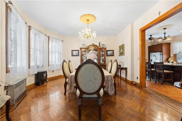 dining space featuring ceiling fan with notable chandelier, radiator heating unit, and baseboards