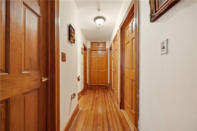 hall with baseboards and light wood-style floors