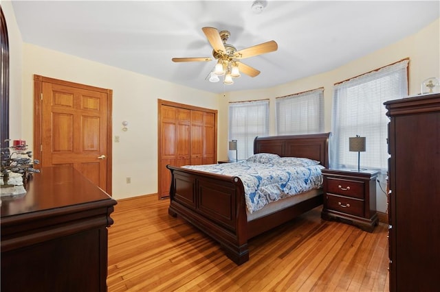 bedroom with ceiling fan, light wood finished floors, and a closet