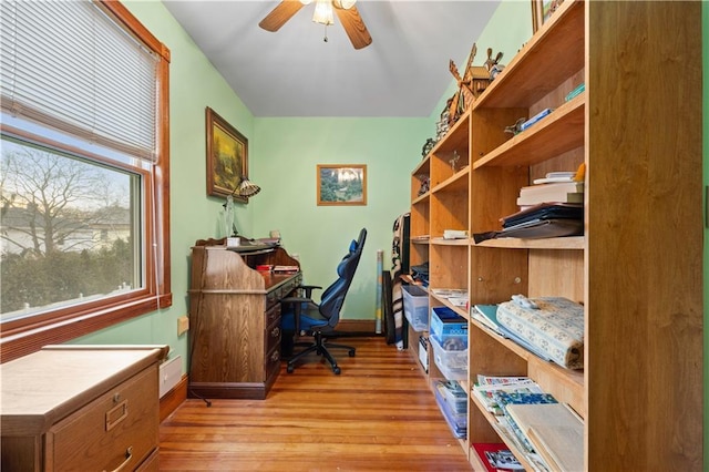 home office with light wood finished floors, a ceiling fan, and baseboards