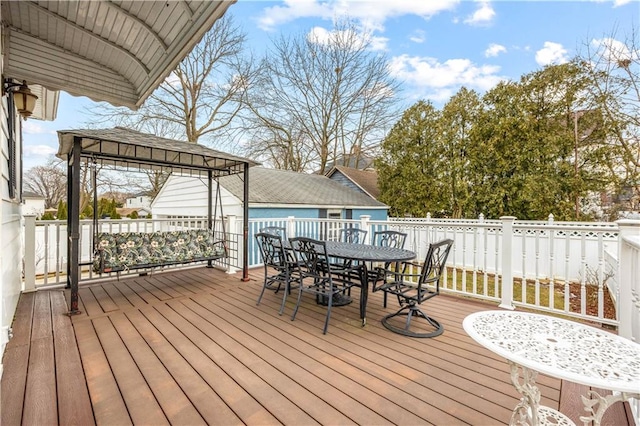 wooden terrace featuring outdoor dining space and a gazebo