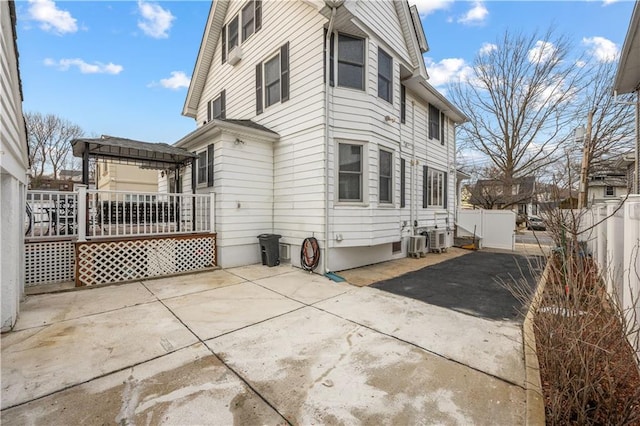 view of property exterior with a patio area, a fenced backyard, a deck, and a pergola