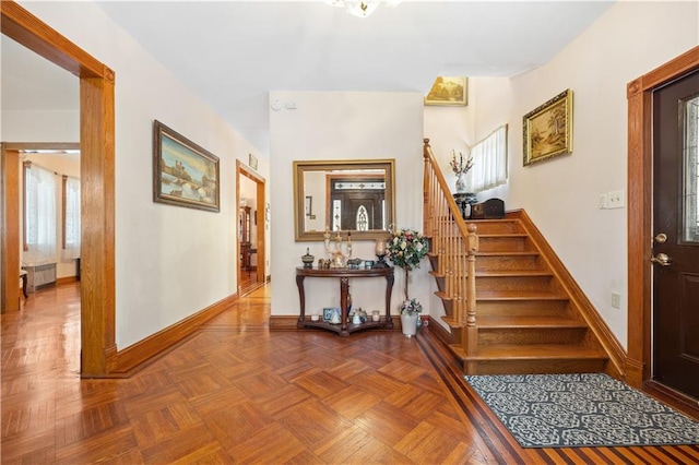 foyer featuring baseboards, stairway, and radiator