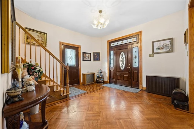 foyer entrance with an inviting chandelier, radiator heating unit, stairs, and baseboards