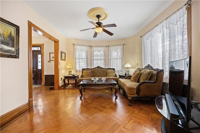 living area with ceiling fan and baseboards