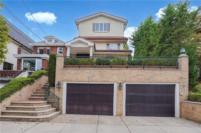 view of front of property with a garage, brick siding, driveway, and stairs