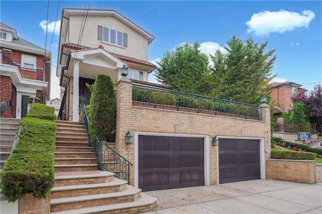 view of front of property with brick siding, stucco siding, stairway, an attached garage, and driveway