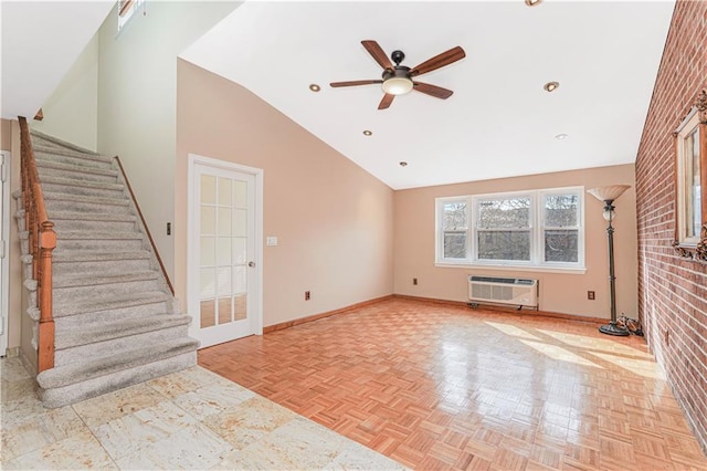 unfurnished living room with high vaulted ceiling, a ceiling fan, baseboards, stairway, and a wall mounted AC