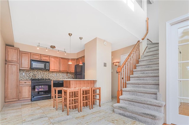 kitchen featuring a breakfast bar, hanging light fixtures, brown cabinets, black appliances, and tasteful backsplash