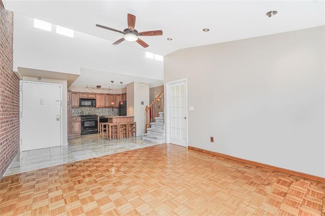 unfurnished living room featuring baseboards, stairs, high vaulted ceiling, and a ceiling fan