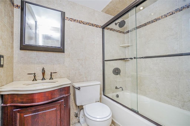 bathroom featuring tile walls, shower / bath combination with glass door, vanity, and toilet