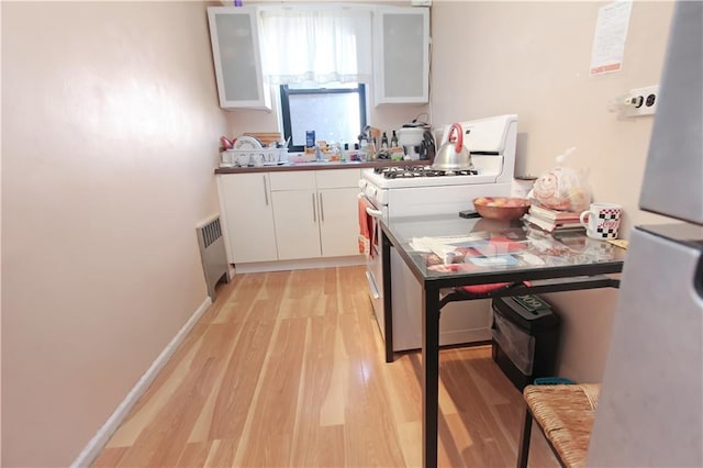 kitchen with white range with gas stovetop, baseboards, white cabinets, radiator heating unit, and light wood-style flooring