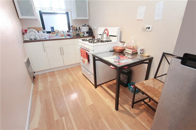 2807 Kings Hwy Unit 3D, Brooklyn, NY 11229 - kitchen with white cabinets, light wood finished floors, white range with gas cooktop, and a sink