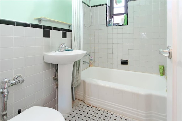 bathroom featuring toilet, tile patterned flooring, tile walls, and shower / bathtub combination