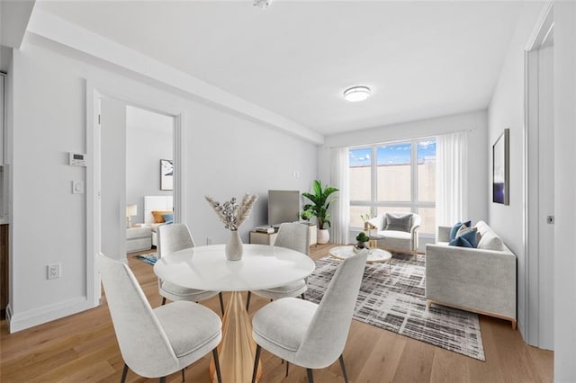 dining space with light wood-style flooring and baseboards