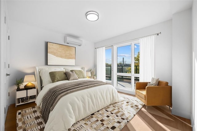 bedroom featuring access to outside, an AC wall unit, and wood finished floors