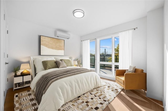 bedroom featuring a wall mounted air conditioner, access to outside, and wood finished floors