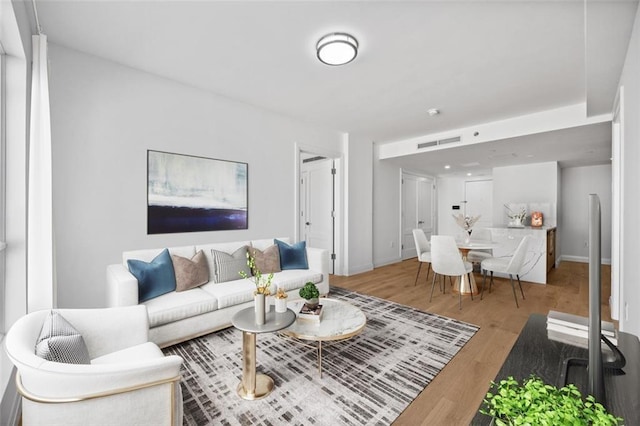 living room featuring wood finished floors, visible vents, and baseboards