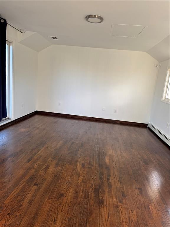 empty room with baseboards, attic access, dark wood finished floors, and vaulted ceiling