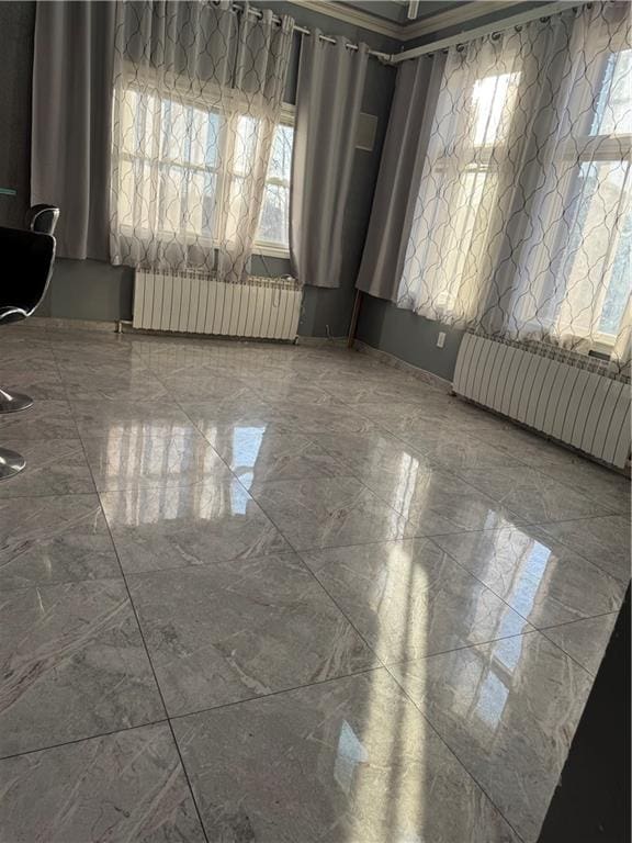 empty room featuring marble finish floor and radiator heating unit