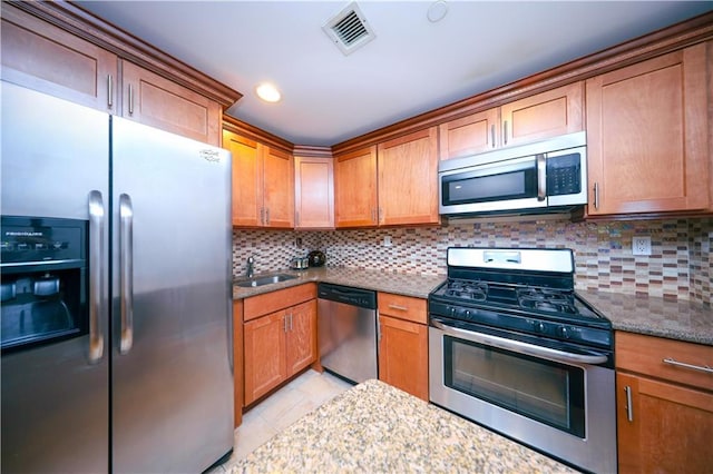 kitchen with appliances with stainless steel finishes, visible vents, a sink, and tasteful backsplash