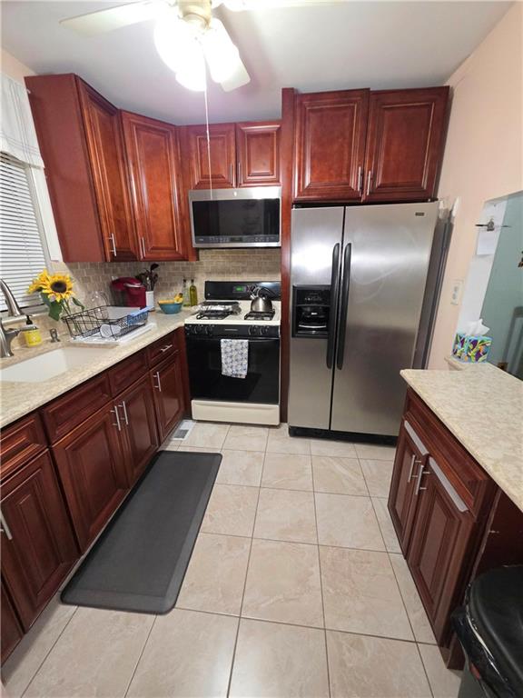 kitchen with light tile patterned floors, decorative backsplash, appliances with stainless steel finishes, light countertops, and dark brown cabinets