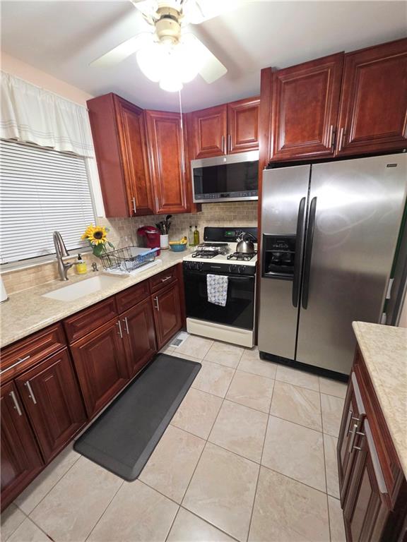 kitchen with a sink, light countertops, appliances with stainless steel finishes, dark brown cabinets, and tasteful backsplash