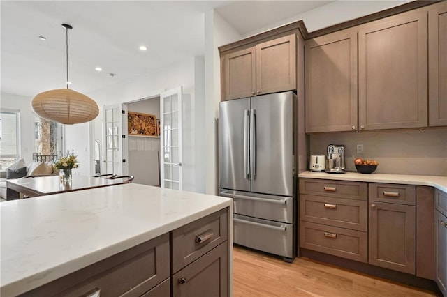 kitchen with decorative light fixtures, light stone counters, freestanding refrigerator, recessed lighting, and light wood finished floors