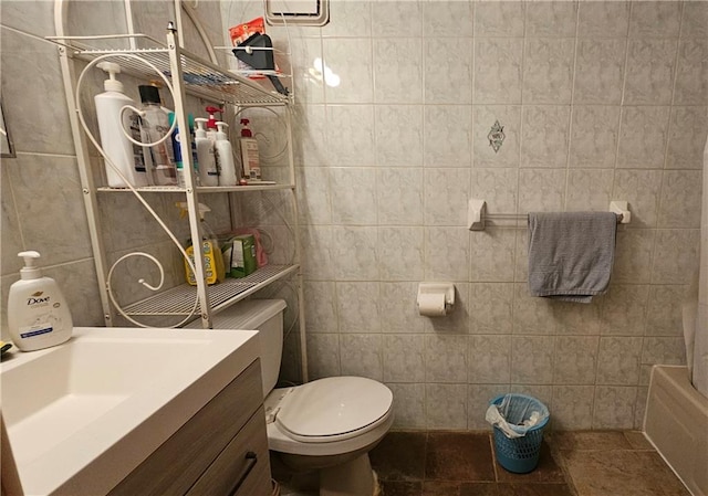 bathroom with tile walls, toilet, vanity, and tile patterned floors