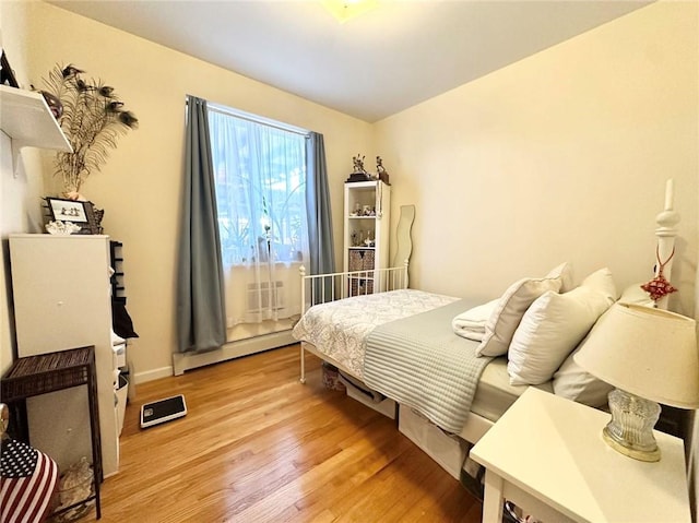 bedroom featuring light wood-type flooring and a baseboard heating unit