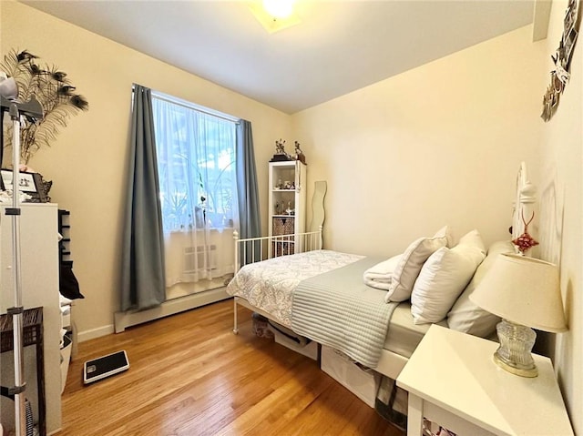 bedroom with a baseboard radiator and wood finished floors