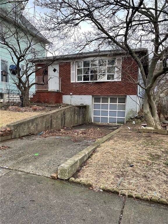 view of front of house with driveway, an attached garage, and brick siding